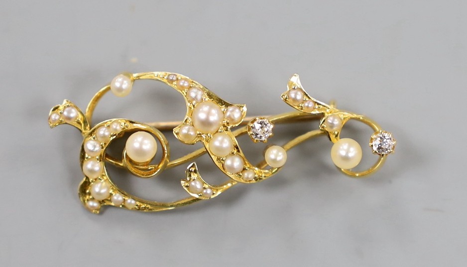 An 18ct, diamond and graduated seed pearl set scroll brooch, 36mm, gross weight 4 grams.